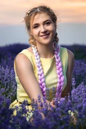 Portrait of a beautiful and sexy girl with long braids in a lavender field. Sunset in the...