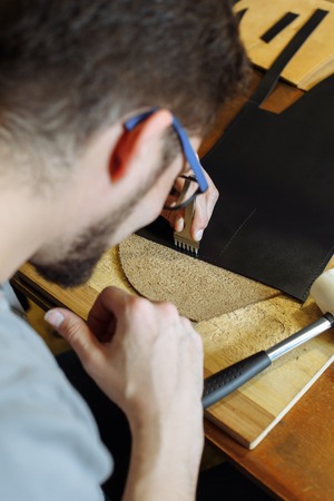 Leather craftsman working with natural leather. Handmade concept. Concept of small business to create leather products. Vertically framed shot.の写真素材