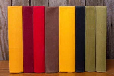 A pile of old colorful books on table. On a wooden background.の写真素材