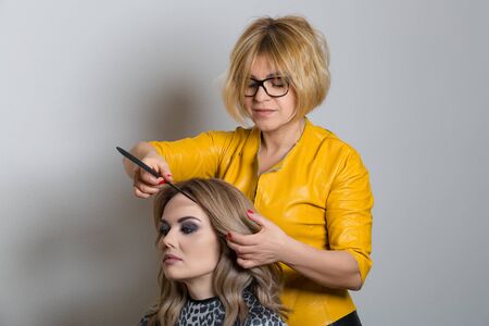 Hairdresser combing hair of client. Horizontally framed shot.の写真素材