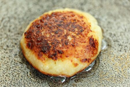 One syrniki is fried in a frying pan. Traditional in Ukraine, Belarus and Russia. Concept of a healthy homecooked meal. Horizontally framed shot.の写真素材
