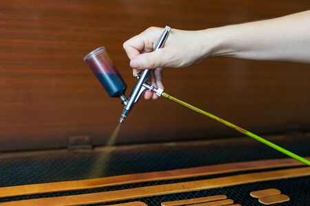 Leather craftsman causes paint on straps. Spray gun with brown paint. Handmade concept. Concept of small business to create leather products. Horizontally framed shot.の写真素材