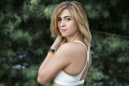 Beautiful young athlete on the background of spruce. The concept of a healthy lifestyle and sports. Horizontally framed shot.の写真素材