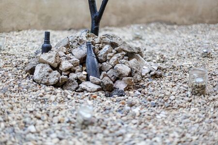 An interesting artistic composition of stones, branches and bottles. Horizontally framed shot.
