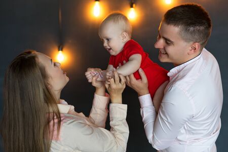 Parents play and indulge with their child. Mom, dad and baby. Portrait of young family. Happy family...