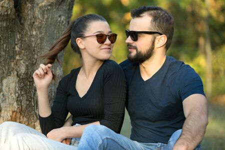 Portrait of a man and a woman in sunglasses in the woods. Young stylish couple on the background of nature. Warm autumn evening in the forest. Horizontally framed shot.の写真素材
