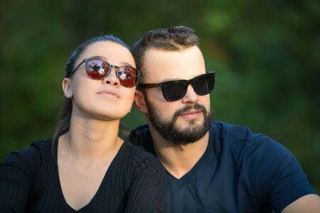 Portrait of a man and a woman in sunglasses in the woods. Young stylish couple on the background of nature. Warm autumn evening in the forest. Horizontally framed shot.の写真素材