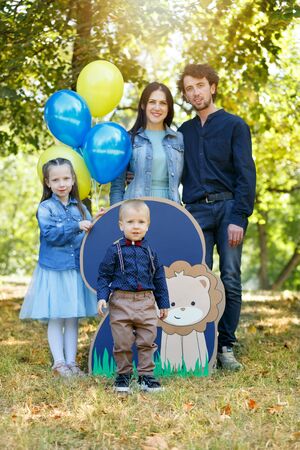 Family life. Portrait of parents and their children in the Park. Birthday of a two year old boy. Decor with the number two with lion and balloons. Vertically framed shot.の写真素材
