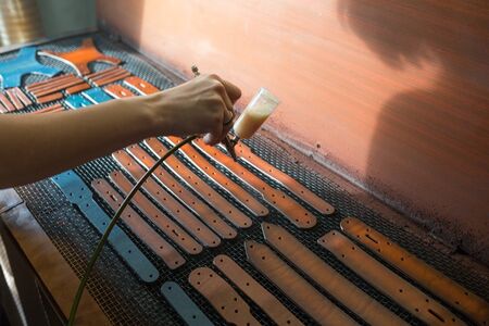 Leather craftsman causes paint on straps. Spray gun with brown paint. Handmade concept. Concept of...