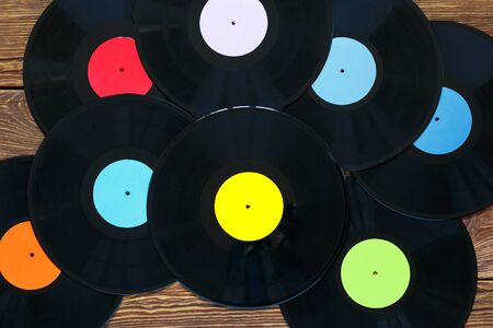 Retro vinyl discs records on wood table background. Multicolored labels. Top view. Horizontally framed shot.の写真素材