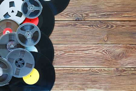 Old vintage bobbins and vinyl records on a wood table background. Multicolored labels. Top view. Place to copy space. Horizontally framed shot.の写真素材