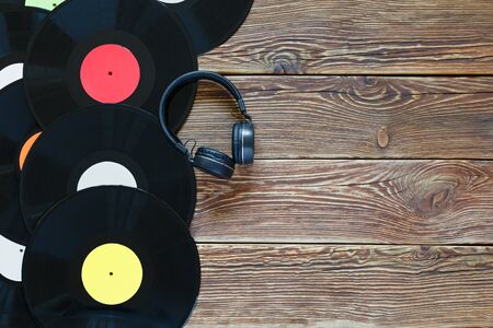 Retro vinyl discs records and headphones on wood table background. Multicolored labels. Top view. Place to copy space. Horizontally framed shot.の写真素材