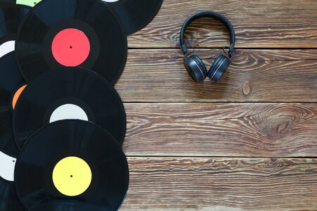 Retro vinyl discs records and headphones on wood table background. Multicolored labels. Top view. Place to copy space. Horizontally framed shot.の写真素材