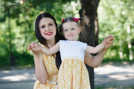 Mom and her daughter in the Park. A woman hugs a girl. Nature in the background. Horizontally framed shot.の写真素材