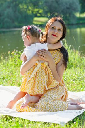 Mother and daughter in the Park by the lake. A girl embraces a woman. Vertically framed shot.の写真素材