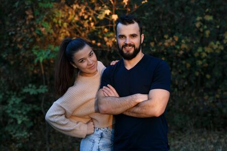 Young beautiful couple in the Park. They are illuminated by a ray of sunlight. In the background autumn forest. Horizontally framed shot.の写真素材