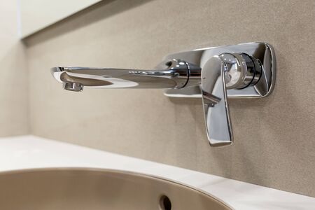 Metal modern faucet built into the wall. Brown sink. Minimalistic design in the bathroom....