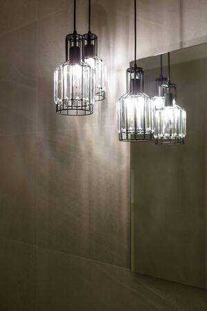 Ceiling light. Modern three-lamp chandelier. Lamp in the bathroom. Reflected in the mirror. Vertically framed shot.の写真素材