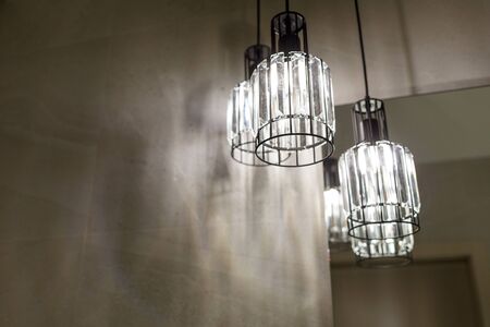 Ceiling light. Modern three-lamp chandelier. Lamp in the bathroom. Reflected in the mirror. Horizontally framed shot.の写真素材