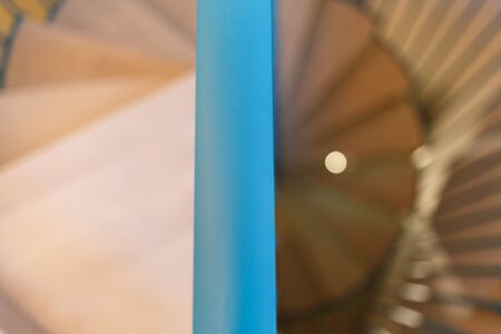 Spiral staircase, forged green handrail and wooden steps in modern home. In the foreground is a railing. Horizontally framed shot.の写真素材