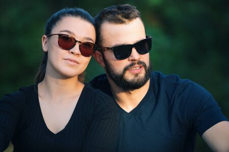 Portrait of a man and a woman in sunglasses in the woods. Young stylish couple on the background of nature. Warm autumn evening in the forest. Horizontally framed shot.の写真素材