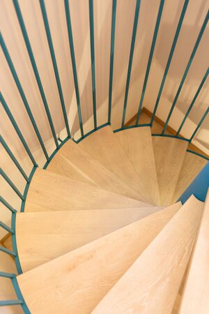 Spiral staircase, forged green handrail and wooden steps in modern home. Vertically framed shot.の写真素材