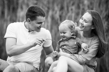 Family life. Portrait of parents and their son on the background of nature. Walk in park. Happy family leisure outdoors. Horizontally framed shot.の写真素材