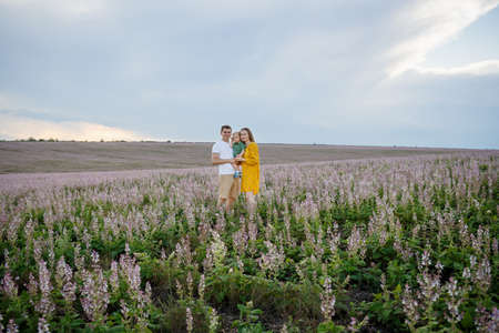 Young family with a baby on a lavender field background. Happy family leisure outdoors. Horizontally framed shot.の写真素材