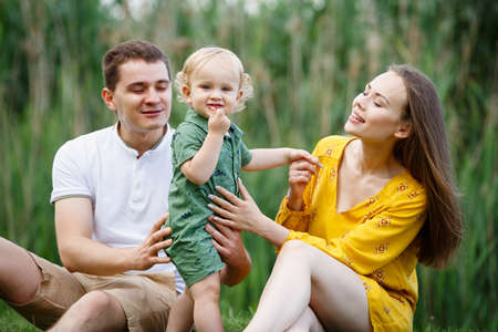 Family life. Portrait of parents and their son on the background of nature. Walk in park. Happy...