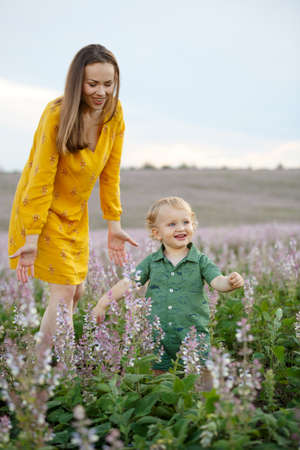 Young mother with a baby on a lavender field background. Happy family leisure outdoors. Vertically framed shot.の写真素材