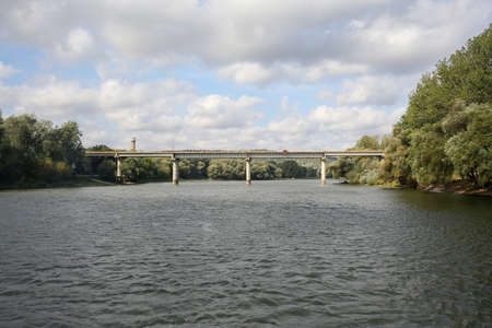 River bridge. A steady flow of water. Trees on both sides of the river. Horizontally framed shot.の写真素材
