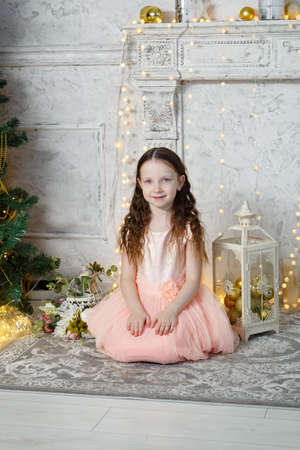 Little cute girl sitting at the Christmas tree. New Year room. Christmas good mood. Lifestyle, family and holiday. Horizontally framed shot. Vertically framed shot.の写真素材