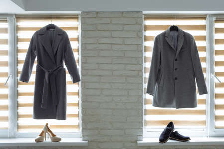 Two coats and shoes on background of window. Preparation for wedding. Horizontally framed shot.の写真素材