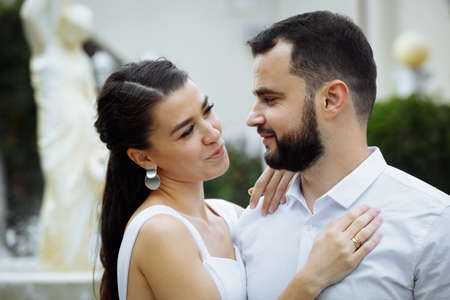 Stylish couple gently hugging on the background of the fountain. Happy sensual wedding couple embracing. Romantic moments of newlyweds. Horizontally framed shot.の写真素材
