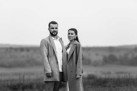 Stylish couple in gray coats on the background of nature. Happy sensual wedding couple. Romantic moments of newlyweds. Horizontally framed shot.の写真素材