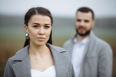 Stylish couple in gray coats on the background of nature. Focus to foreground. Horizontally framed shot.の写真素材