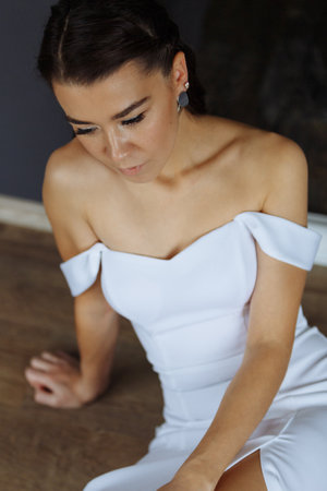 Portrait of an attractive young bride. Women in a wedding dress is sitting on the floor. Vertically framed shot.の写真素材