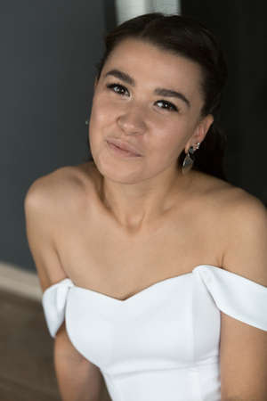 Portrait of an attractive young bride. Women in a wedding dress is sitting on the floor. Vertically framed shot.の写真素材