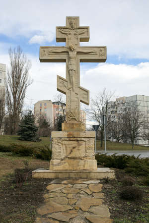 Cross Orthodox religion in front of a city. Stone monument of the Crucifixion of Christ.の写真素材