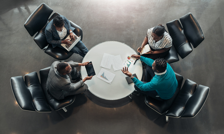 group of business people sitting and discussing statistics during a sit down meeting taking from aboveの写真素材