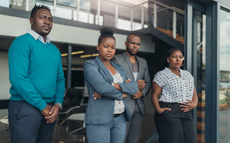 Portrait of a confident black businesswoman crossing her arms with all african team in the backgroundの写真素材