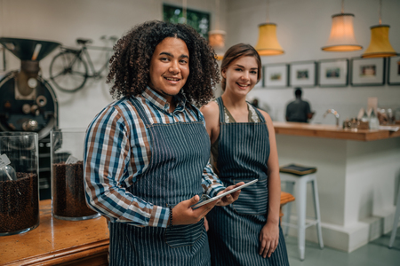 Portrait of entrepreneurs of a coffee roastery and cafe. Mixed race guy holding a tabletの写真素材