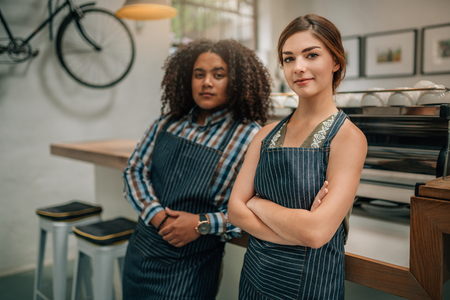 Portrait of two confident baristas with arms crossed at the coffee shopの写真素材