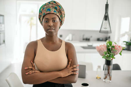 Portrait of a confident Black African woman with her arms crossed looking into the camera. Working from home and wearing a traditional headscarfの写真素材