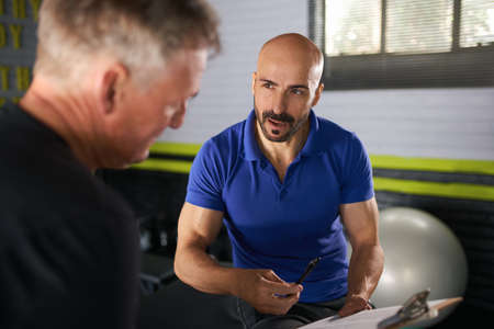Male physio therapist and wellness personal trainer having a consultation with elderly senior man on...