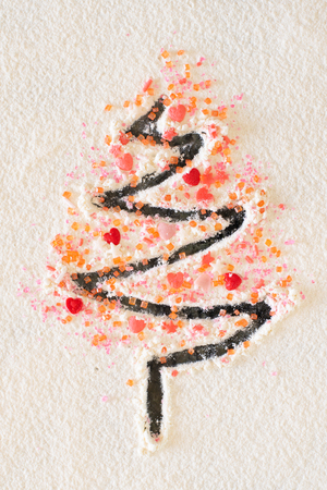 A confectionary finger drawing of a Christmas tree with heart and star sprinkles.の写真素材