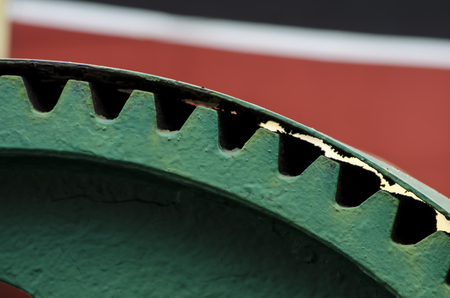 A brightly painted green cog against a red, white and black background.の写真素材