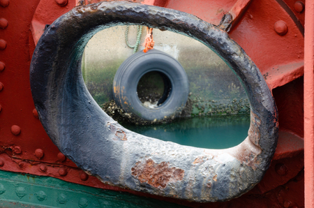 A tyre used for fending ships off the quay is visible in the background through a ship's hawsepipe.の写真素材