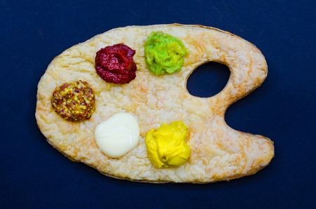Tasty and colourful sauces and relishes on a puff pastry artist's palette - guacamole, tomato, wholegrain dijon mustard, mayonnaise and mustard.の写真素材