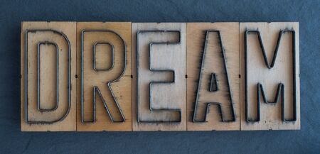 Old wood and steel number plate dies spell out the word DREAMの写真素材